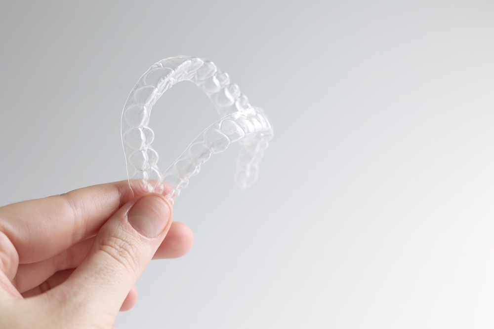 Aligners for straightening teeth on a light background in female hands.