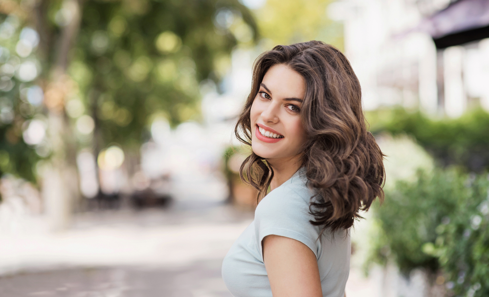 Woman smiling confidently outdoors after dental implant treatment in Virginia Beach 