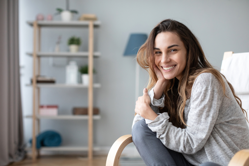 Woman smiling indoors with straight, healthy teeth after orthodontic treatment in Virginia Beach 