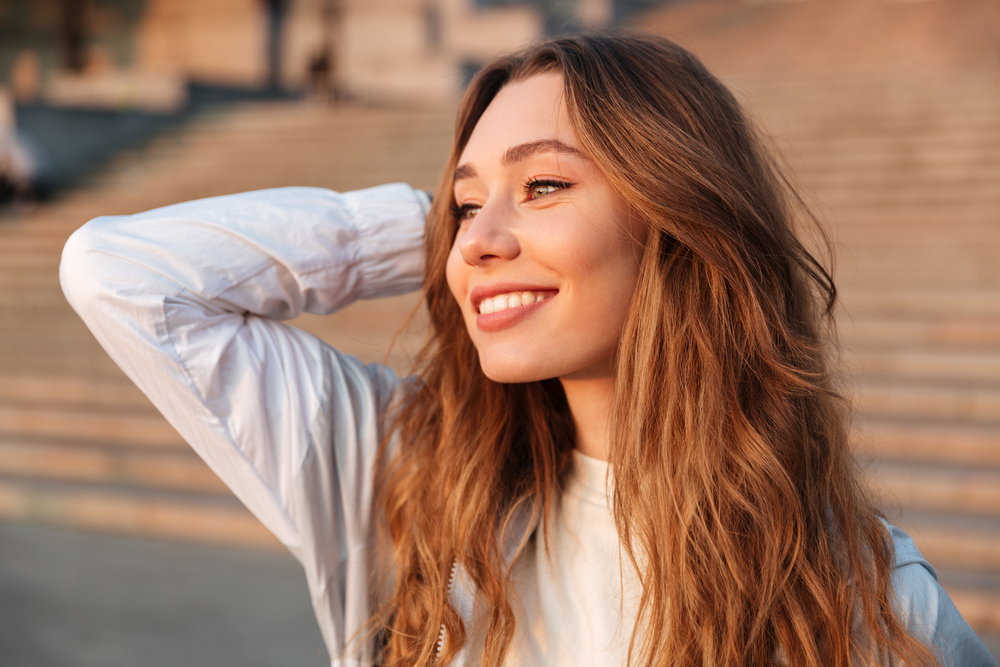 Close up image of Smiling brunette woman in autumn clothes posing outdoors and looking away