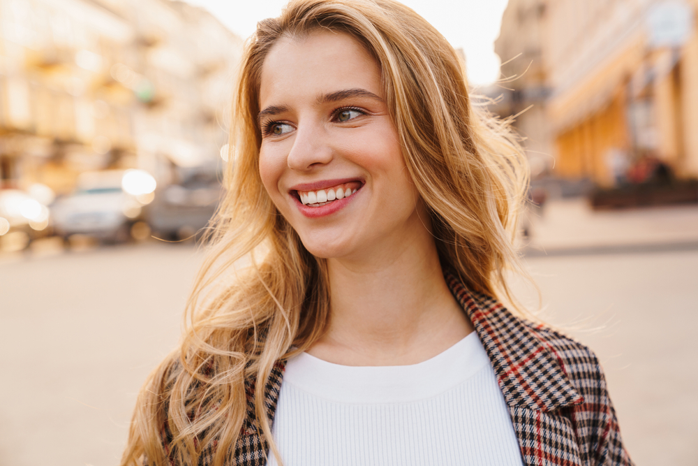 Close up of a smiling blonde young woman walking on a street