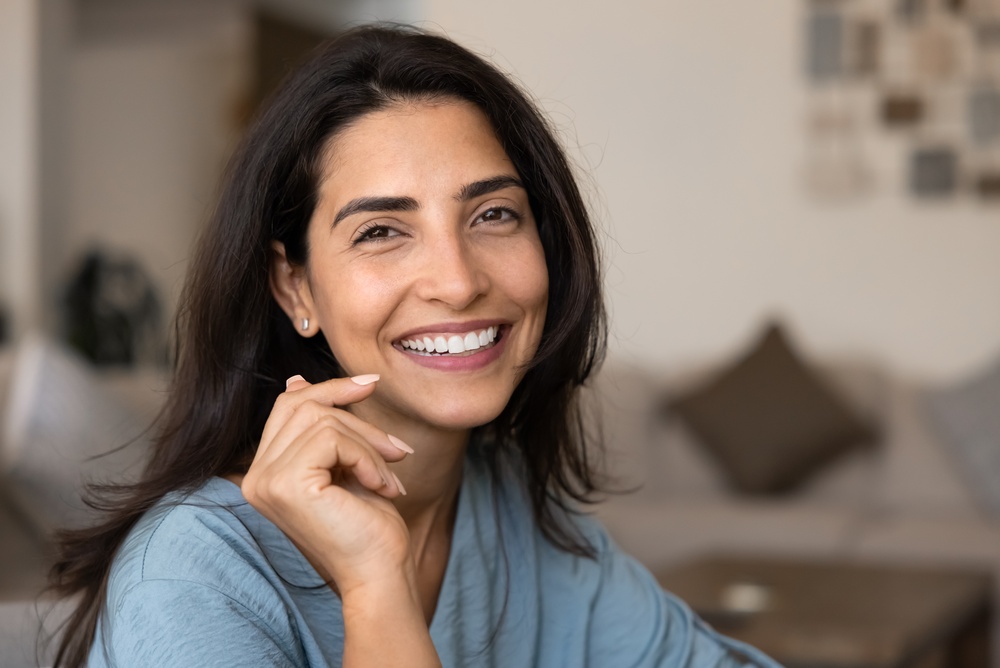 Close-up portrait of Brazilian woman relaxing indoor, look at camera with joyful expression, exuding happiness, enjoy pleasant time at home, advertising dental services while revealing her white teeth