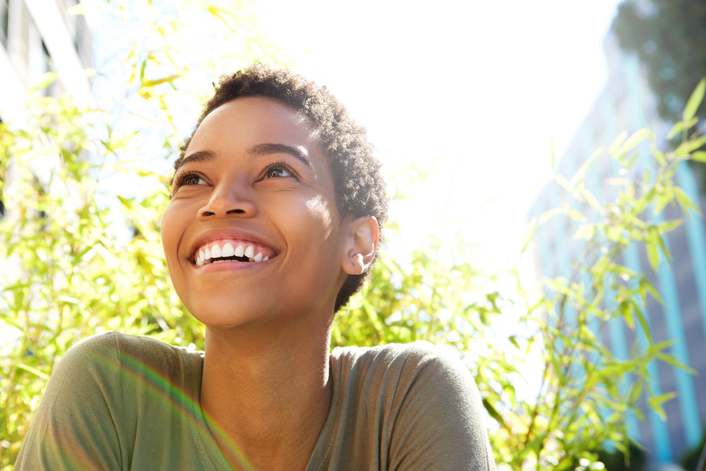 Bright, healthy smile: restorative dentistry in the Hampton Roads community Woman smiling brightly outdoors in natural sunlight, representing the healthy smiles achieved through restorative dentistry in the Hampton Roads community