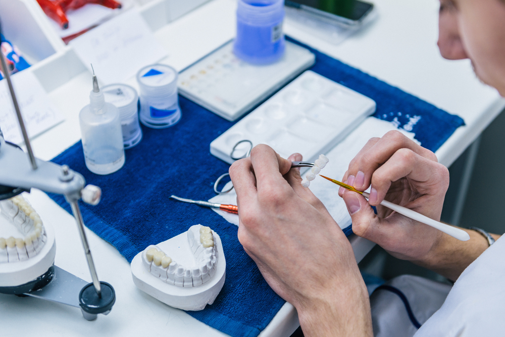 In-house dental lab: restorative dentistry in Hampton Roads Dental lab technician crafting a custom restoration using a tooth colored shade guide at The Foleck Center's in-house dental lab