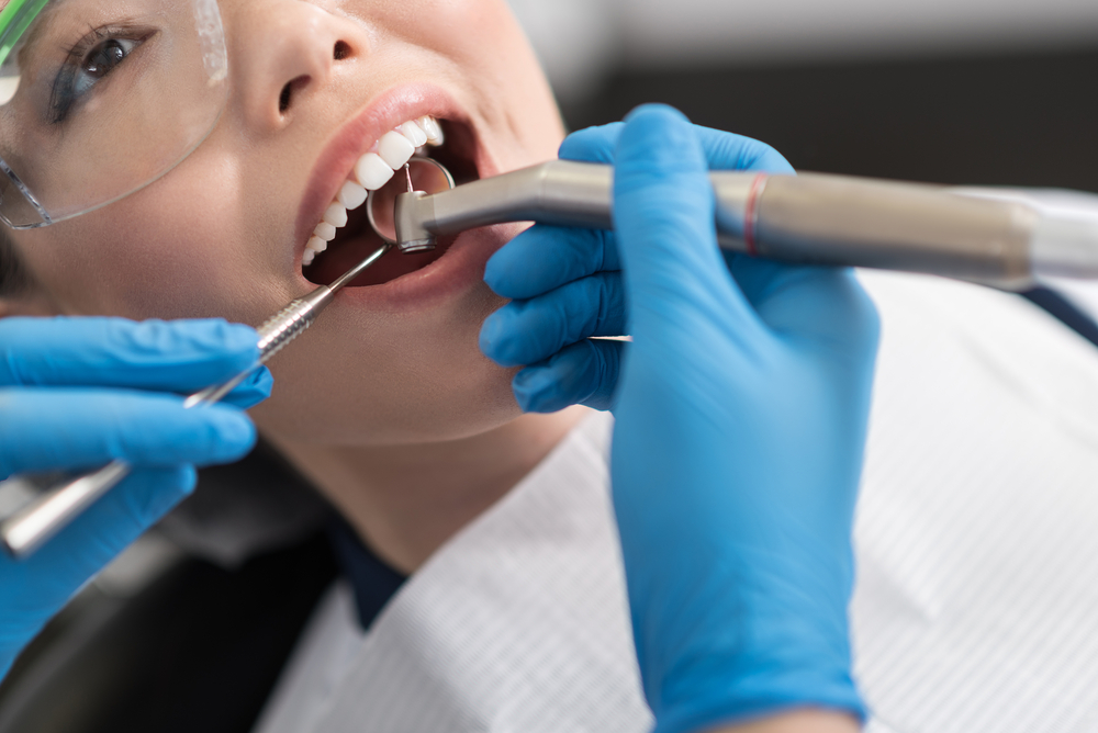 Dentist examining a patient's teeth with dental instruments during an implant procedure in Virginia Beach 