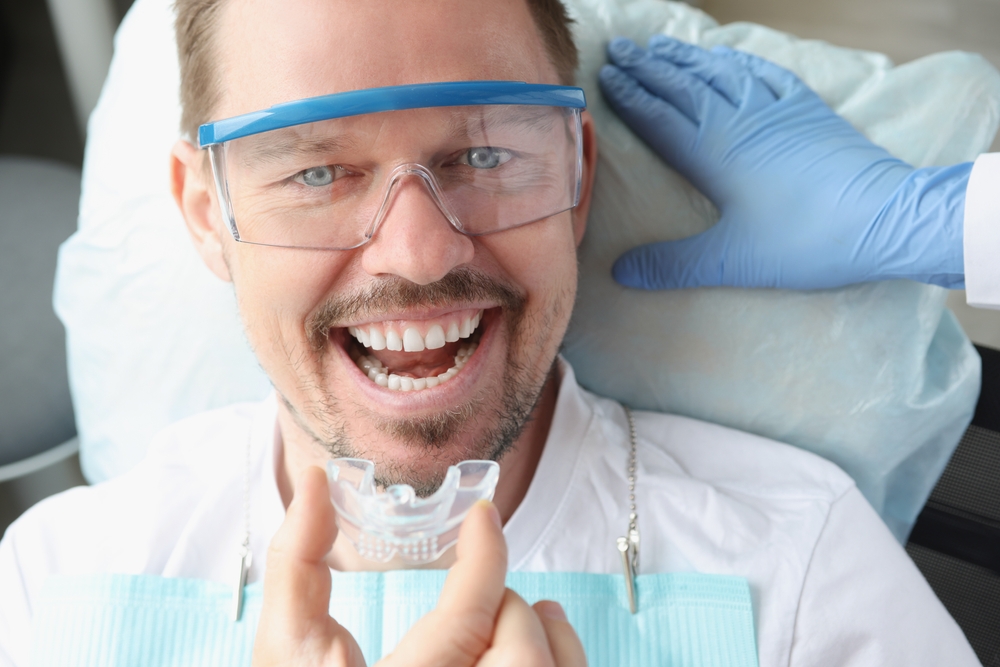 Smiling man holding a night guard fitted during a full-mouth reconstruction visit in Virginia Beach 