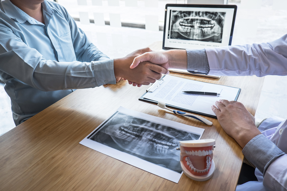 Cosmetic Dentistry Consultation, Virginia Beach Dental Office Dentist and patient shaking hands over dental x-rays during a cosmetic dentistry consultation in Virginia Beach