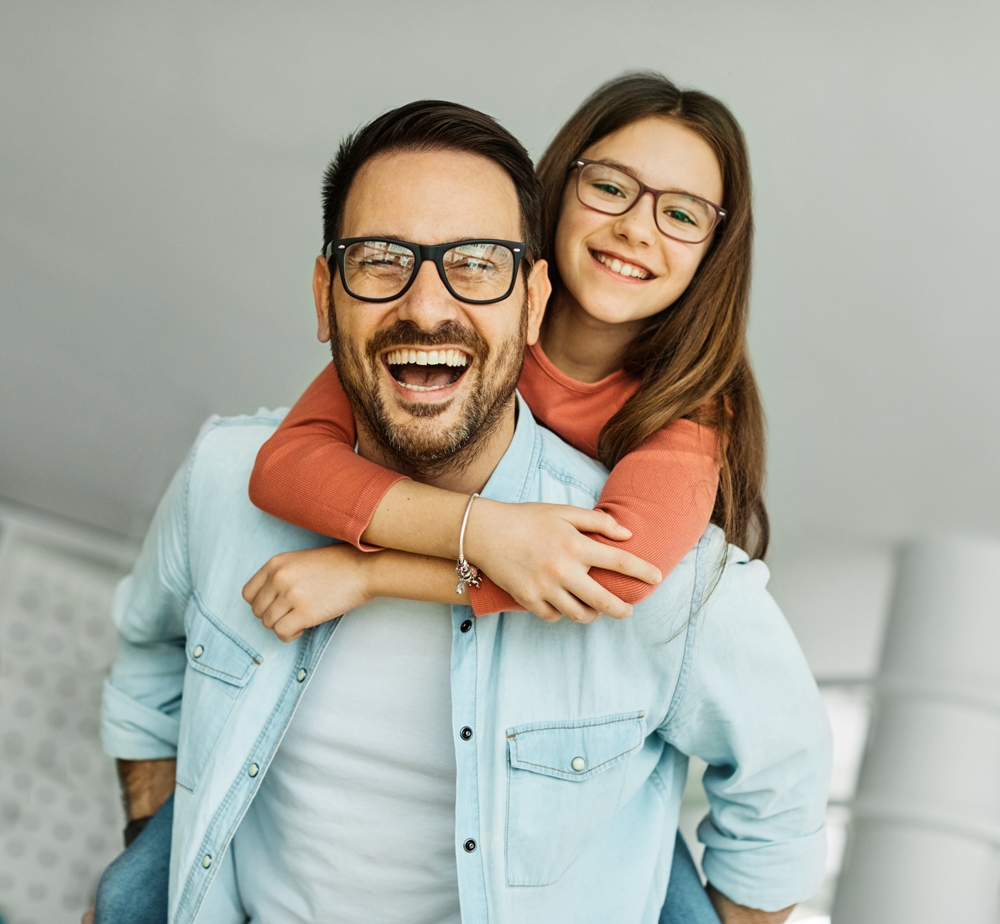 Father and daughter laughing together at home after gum disease treatment in Norfolk 