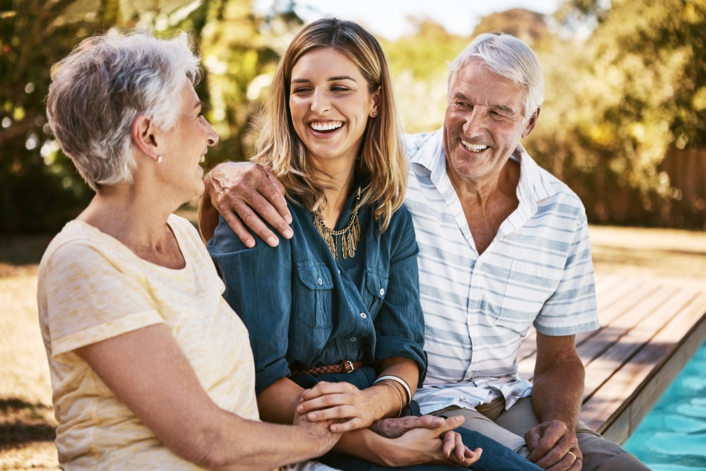 Dental implants for all ages in Norfolk, VA, The Foleck Center Adult woman laughing with her elderly parents outdoors, reflecting confidence and quality of life after dental implant treatment at The Foleck Center, Norfolk, VA