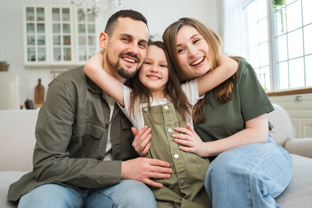 Family embracing and smiling together at home, reflecting the orthodontic care available for the whole family in the Norfolk community 