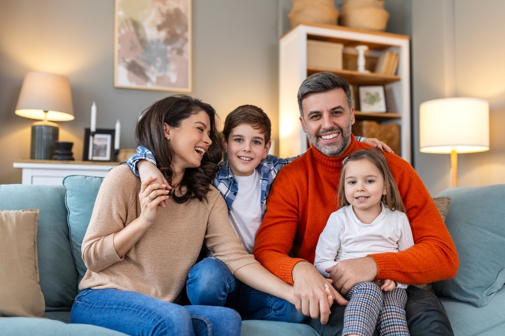 Family dentistry: care for families in the Norfolk community Family smiling together at home, reflecting the family dentistry care available in the Norfolk community