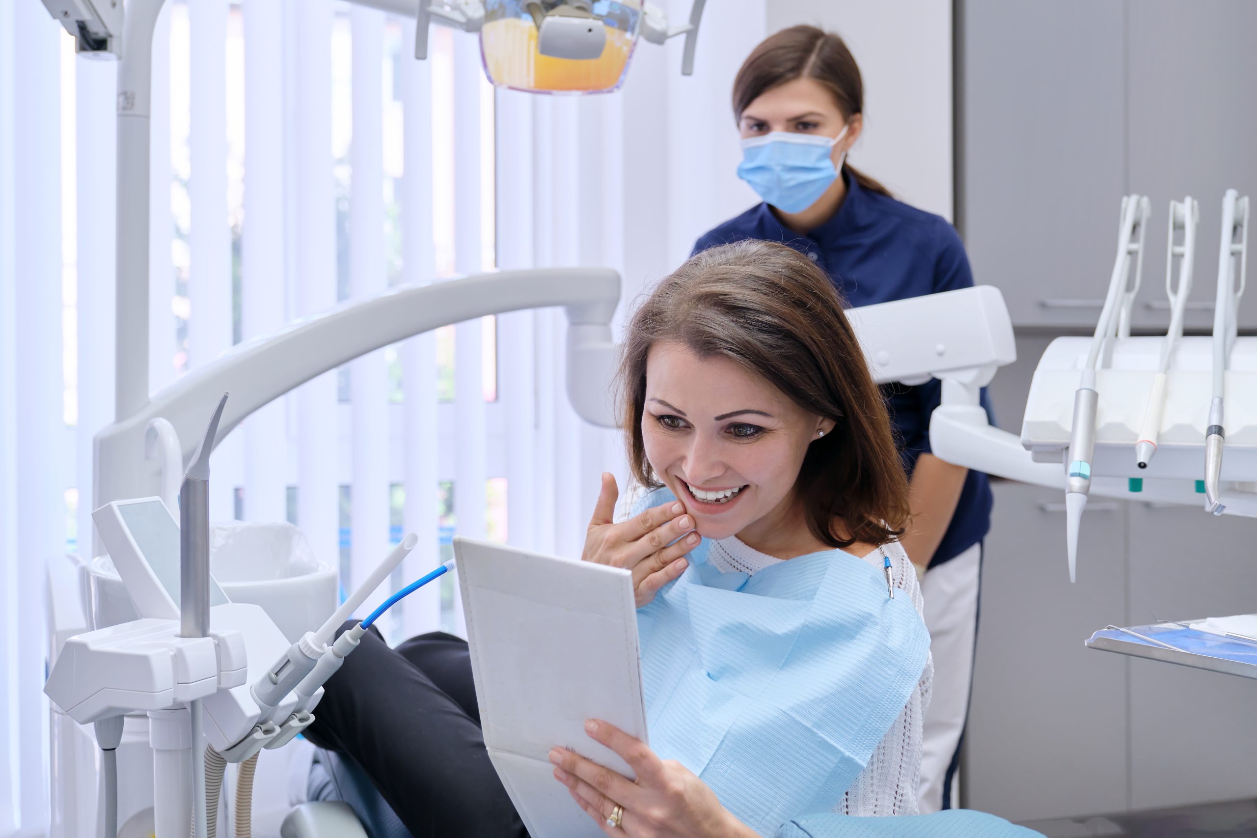 Patient reviewing moderate periodontitis treatment plan at The Foleck Center in Virginia Beach, Norfolk, and Hampton Female dental patient smiling while reviewing treatment results on a tablet at The Foleck Center in Hampton Roads