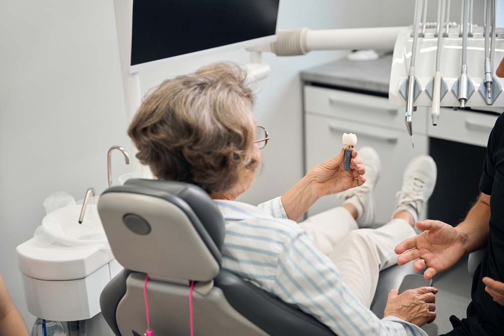 Lady holds model of dental implant in hands
