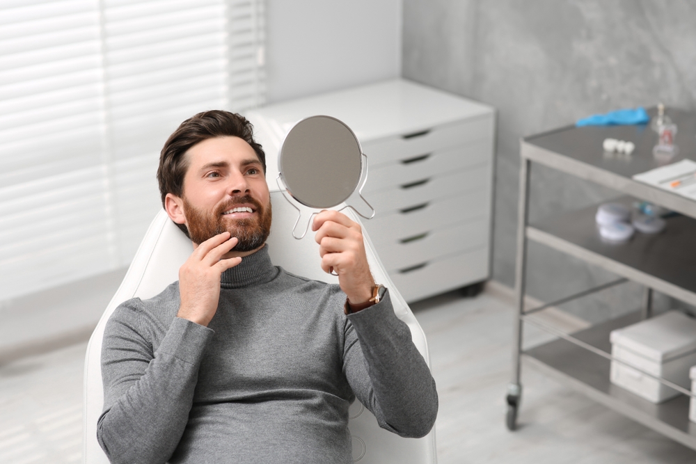Patient viewing his smile in a mirror at our Virginia Beach, VA office 