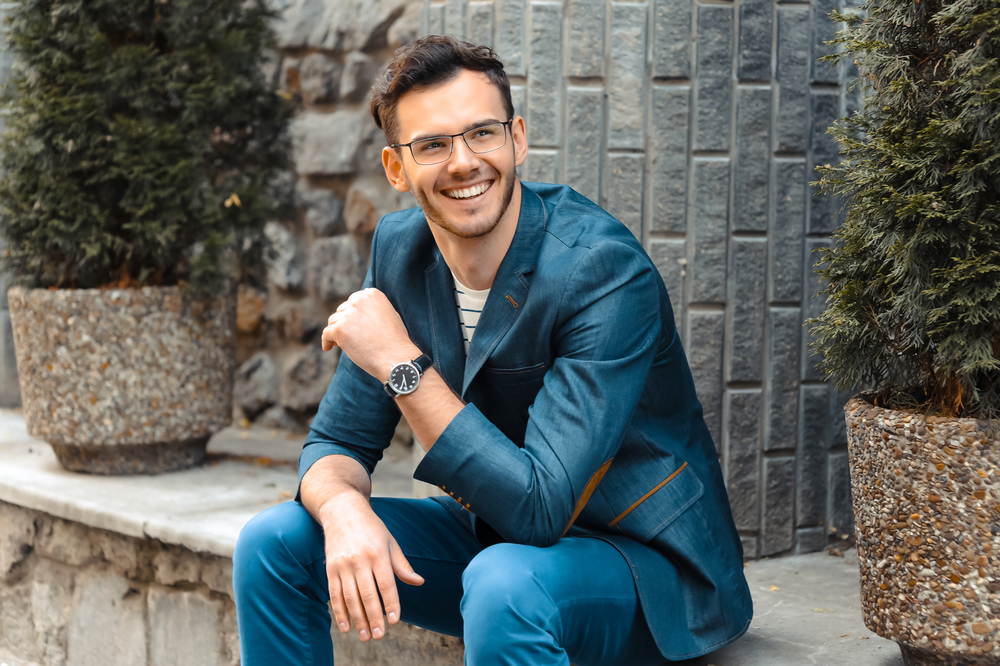 Confident smile: restorative dentistry in the Norfolk community Man in a tailored blue suit smiling confidently outdoors, representing the healthy smiles achieved in the Norfolk community