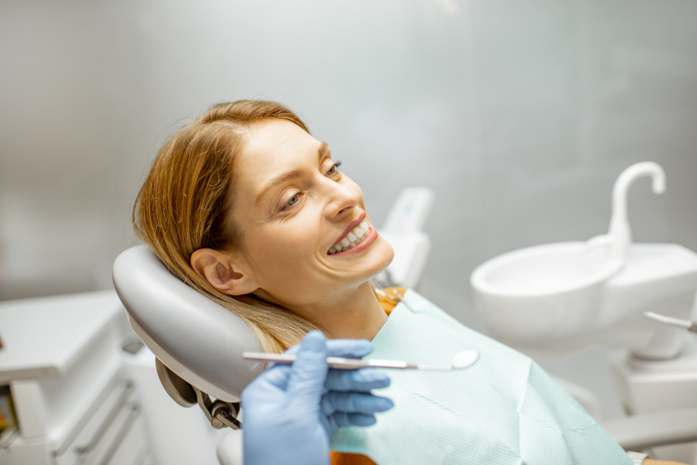 Portrait of a beautiful and cheerful woman sitting as a patient on the dental chair during a medical examination at the dental office