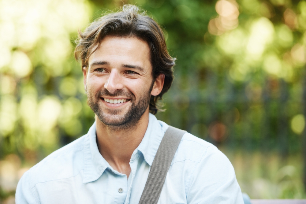 Relax, smile or happy man in park on a bench in summer for holiday vacation or break in garden. Mental health, thinking or face of person in nature resting or waiting in a natural environment