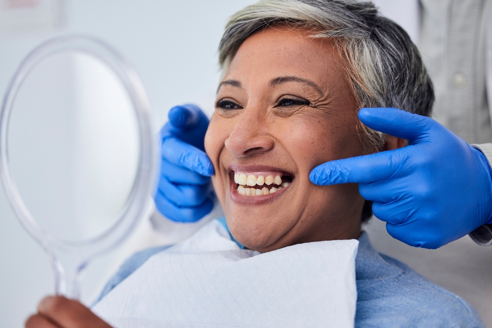 Older woman smiling confidently in the dental chair while a dentist highlights her veneer results at The Foleck Center, Virginia Beach, VA 