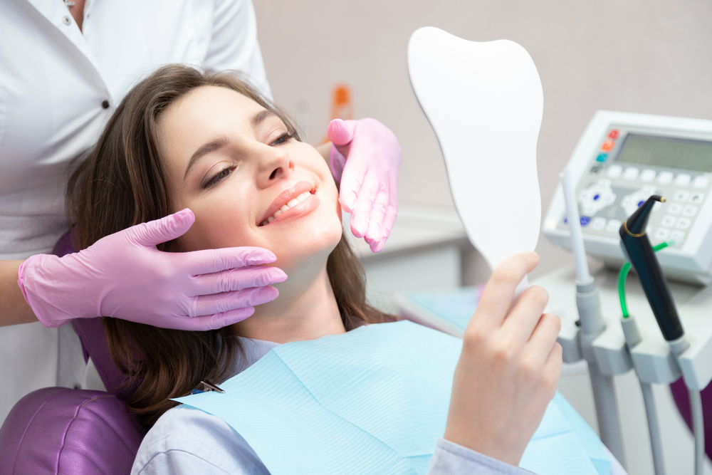 Restorative dentistry results: Hampton Roads patient Patient admiring her smile in a hand mirror during a restorative dentistry visit in Hampton Roads