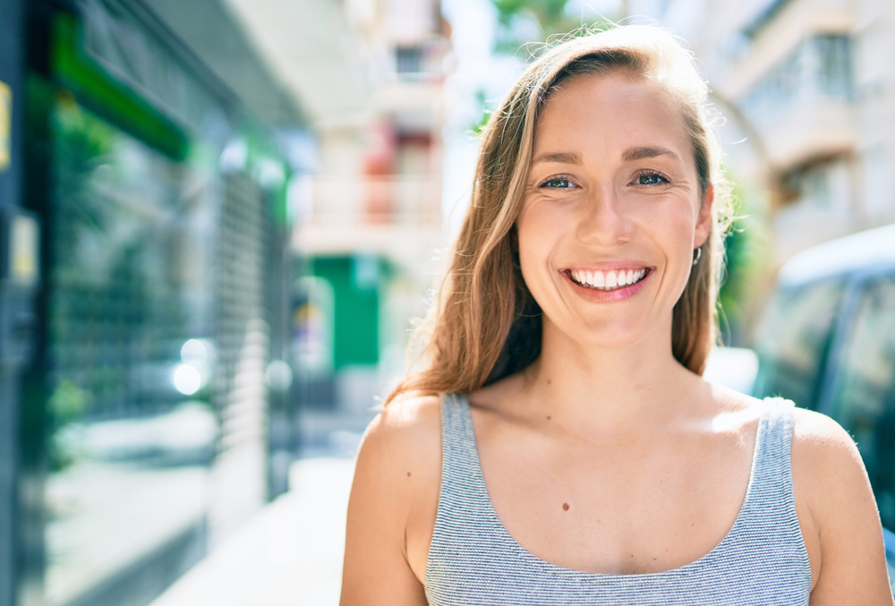 Young blonde woman smiling happy walking at street of city