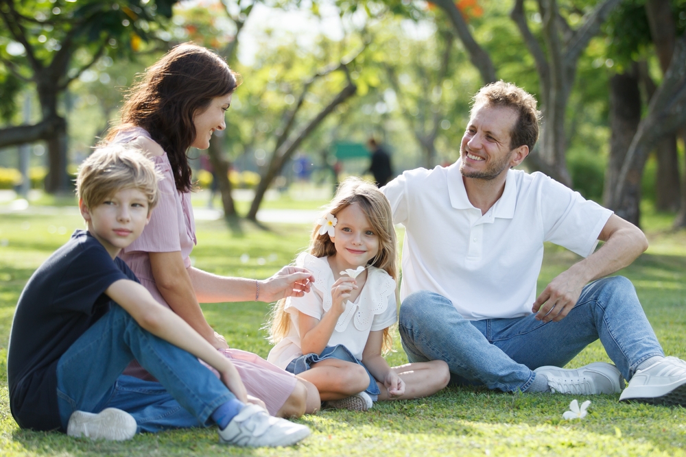 Family Smiles in the Park: Norfolk Community Patient Happy family sitting together in a park after a smile makeover consultation in the Norfolk community