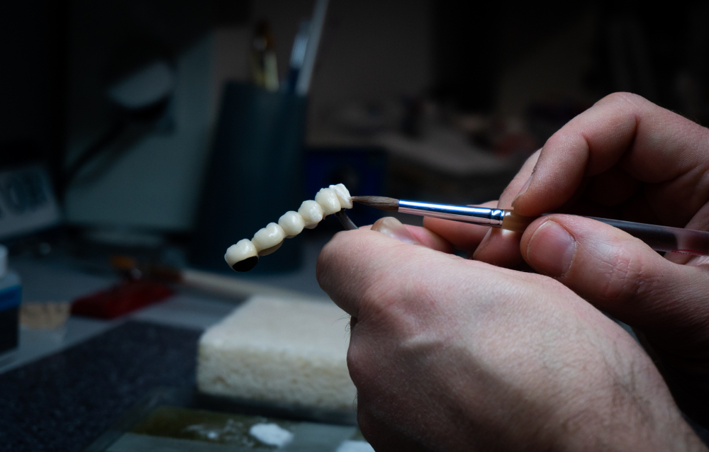 Dental technician hand-finishing a custom porcelain restoration in The Foleck Center's Virginia Beach in-house dental lab 