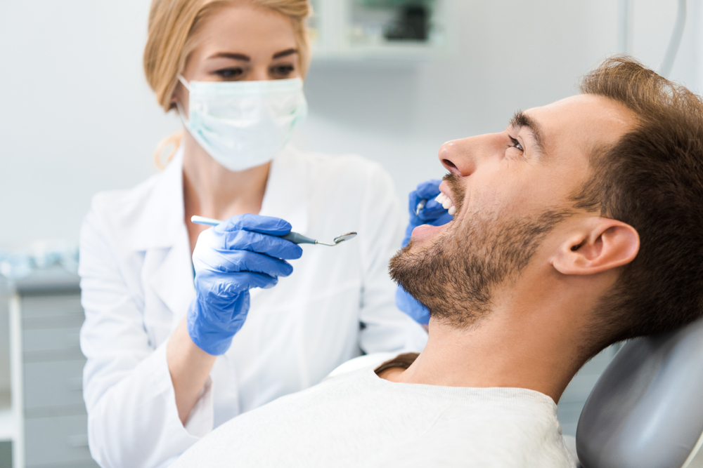 Restorative dental exam: Hampton Roads Dentist examining a patient's teeth with a mirror and explorer during a restorative dentistry visit in Hampton Roads