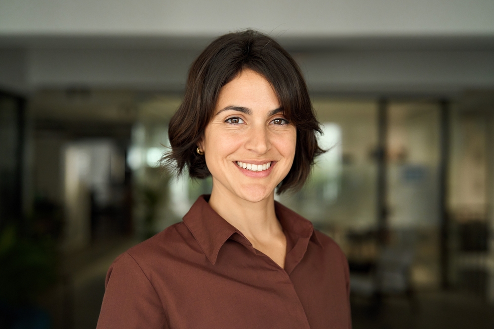 Woman smiling confidently with bright teeth in a professional setting, reflecting veneer results at The Foleck Center, Virginia Beach, VA 