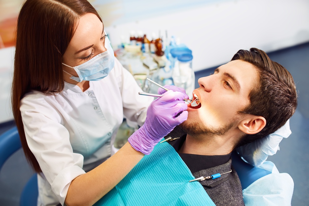 Dentist performing a dental procedure on a male patient at The Foleck Center, Norfolk, VA 