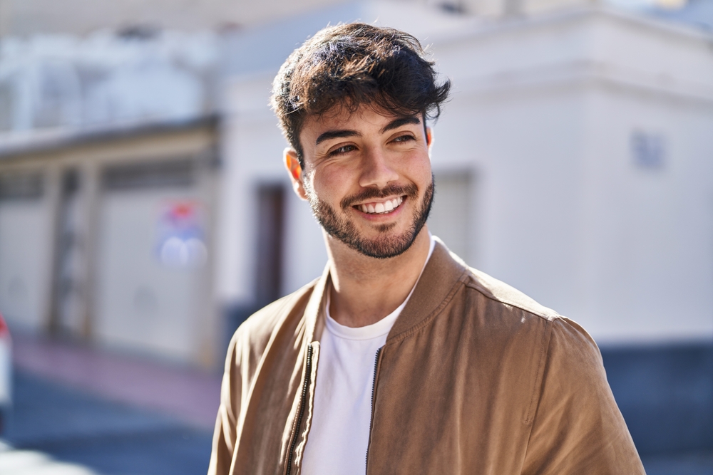 Same-day dental restorations in Virginia Beach, VA, The Foleck Center Young man smiling confidently outdoors after same-day dental restoration at The Foleck Center, Virginia Beach, VA