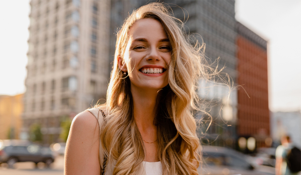 Refreshed, confident look: Botox treatments in Hampton Roads Woman with long blonde hair smiling outdoors on a city street