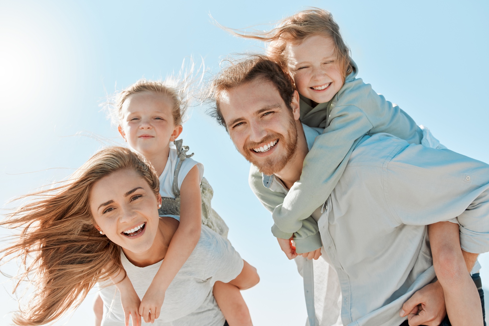 Family Invisalign care in Norfolk, VA, The Foleck Center Family of four laughing together outdoors, representing families served by The Foleck Center, Norfolk, VA