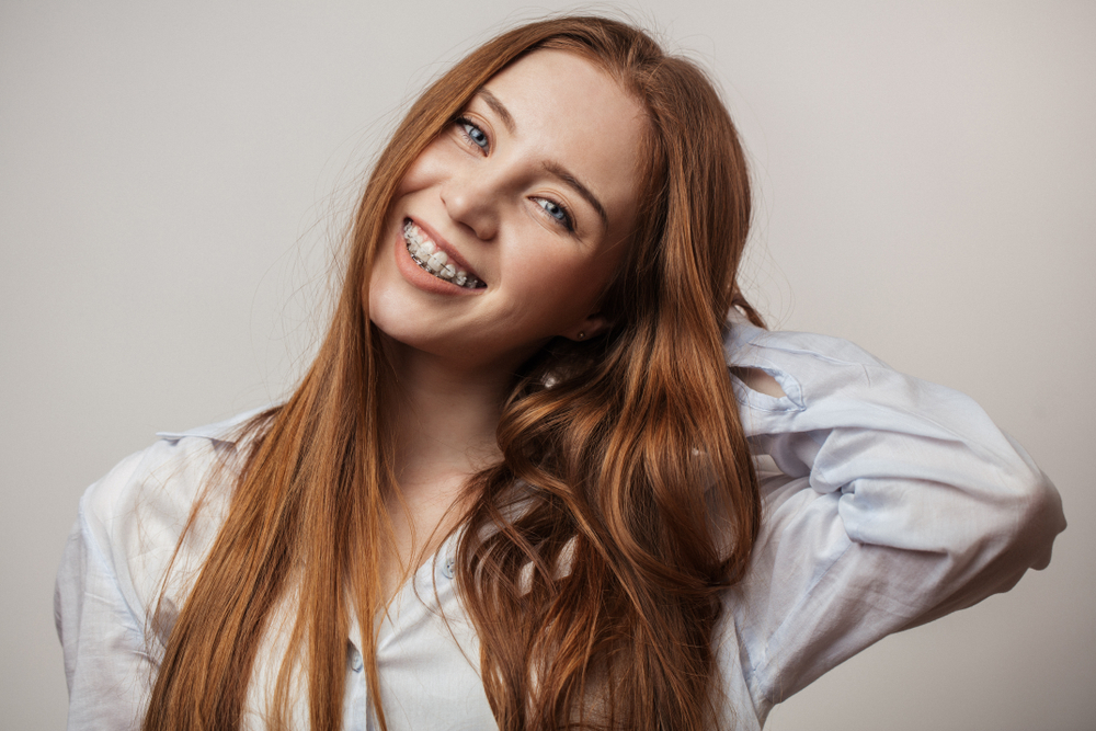 Bright smile with braces: dental care in the Norfolk community Young woman with braces smiling brightly, representing the orthodontic and restorative care available in the Norfolk community