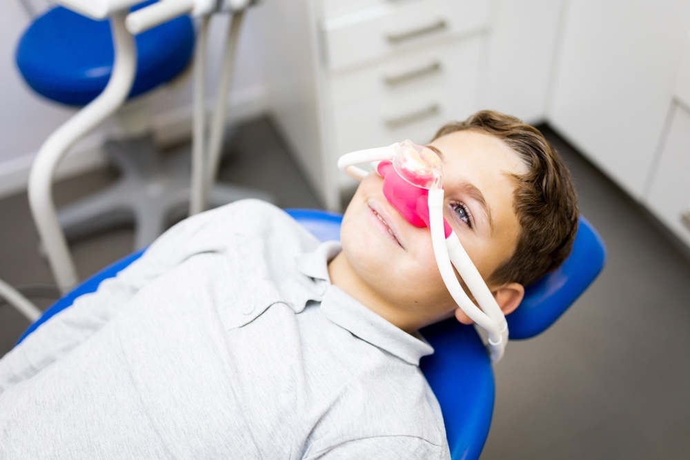 Young boy relaxing in dental chair with nitrous oxide mask during Virginia Beach sedation dentistry appointment at The Foleck Center