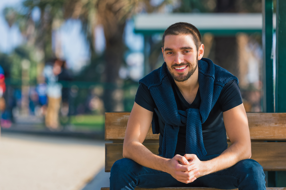 Relaxed smile outdoors in the Hampton community Man sitting on a park bench in the Hampton community
