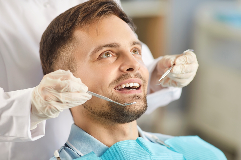Dental exam: family dentistry in Norfolk Dentist examining a patient's teeth with a mirror and explorer at our Norfolk dental office