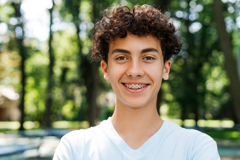 Teenage boy smiling with braces, representing the orthodontic care available in the Norfolk community 