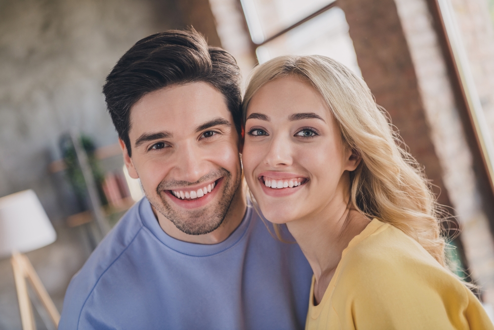 Confident smiles, full mouth reconstruction in Hampton Roads Man and woman smiling cheek to cheek indoors