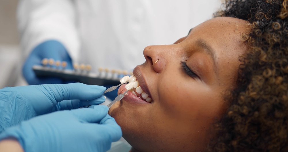 Dental implant crown shade matching in Norfolk, VA, The Foleck Center Dentist matching tooth shade with a dental guide during an implant crown consultation at The Foleck Center, Norfolk, VA