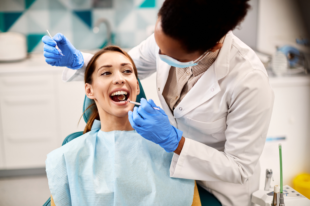 Pre-Whitening Dental Check, Norfolk Dental Office Dentist checking a smiling patient's teeth before a whitening treatment at a Norfolk dental office
