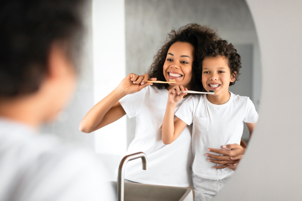 Healthy brushing habits: dental care in the Norfolk community Mother and son brushing their teeth together, reflecting good oral hygiene habits in the Norfolk community