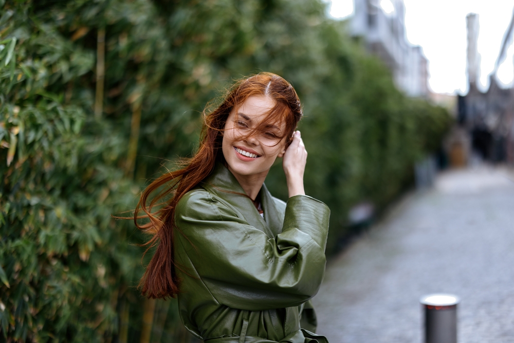 Woman smiling outdoors with straight teeth after Fastbraces treatment in the Bayside community 