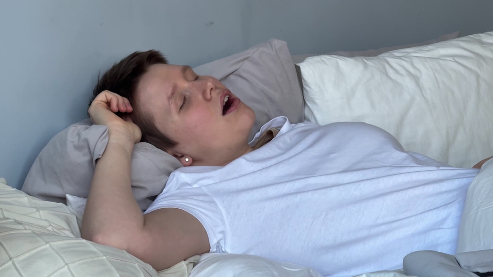 young woman sleeps in bed during the day and has breathing problems, apnea, open mouth, snoringyoung woman sleeps in bed during the day and has breathing problems, apnea, open mouth, snoring